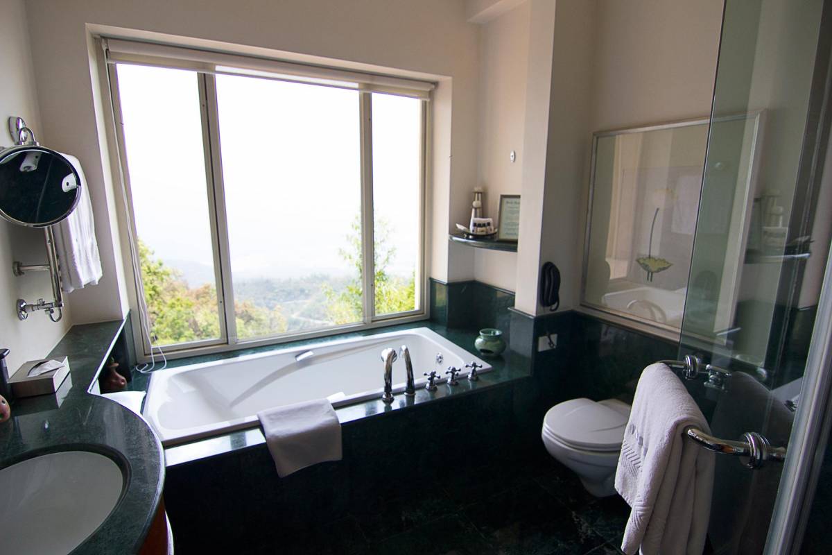 Blick auf die Badewanne mit großer Fensterfront im Hintergrund im Badezimmer einer der Suites im Ananda Hotel