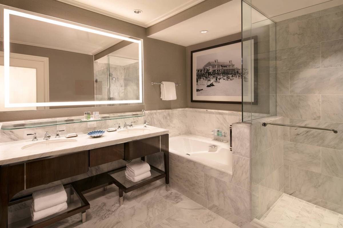Blick auf den Waschtisch, die Badewanne und die Dusche im Badezimmer einer Deluxe Suite im The Breakers Palm Beach